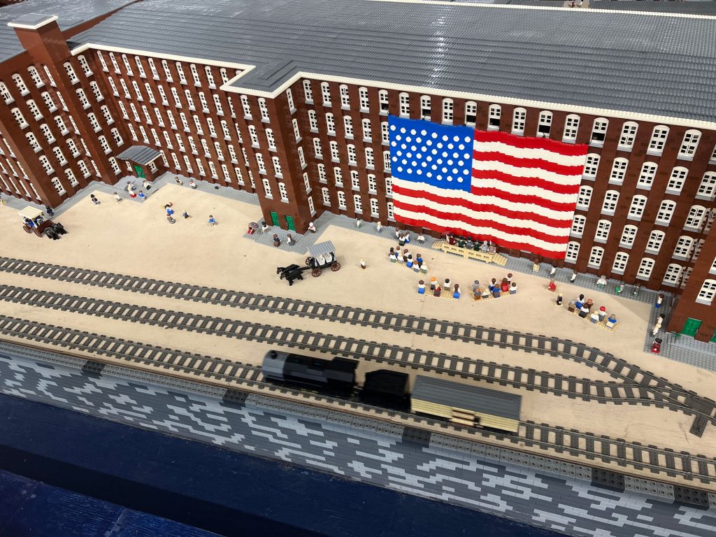 figures gathered at the millyard with the US flag | The LEGO® Millyard Project at SEE Science Center in Manchester, NH